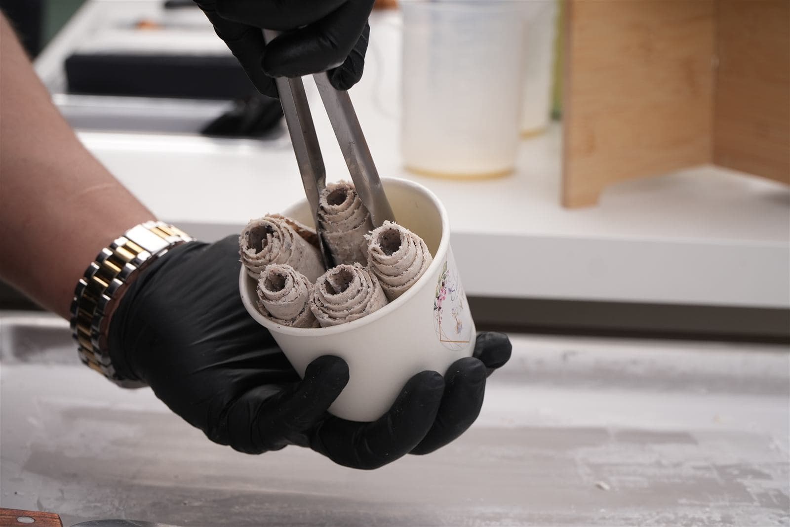 Hand-rolled ice cream rolls being placed into a custom party cup