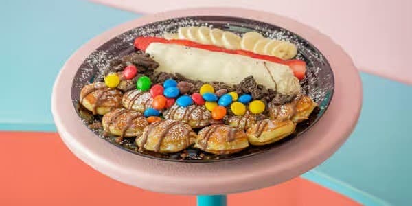 Mini pancake skewers with M&M's, chocolate drizzle, whipped cream, strawberries, and bananas