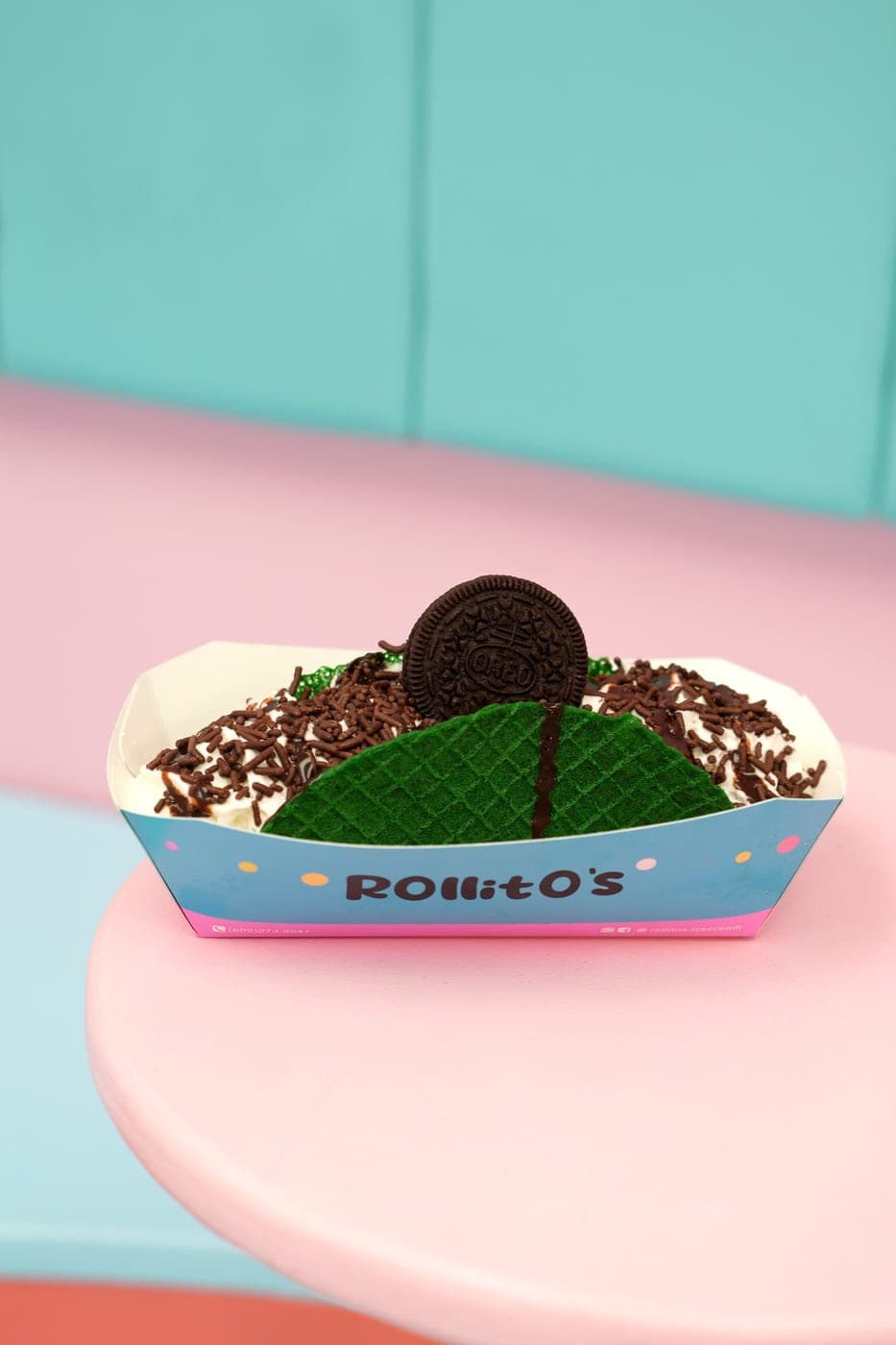 Mint green waffle taco roll with chocolate sprinkles, fudge drizzle, and an Oreo cookie on top