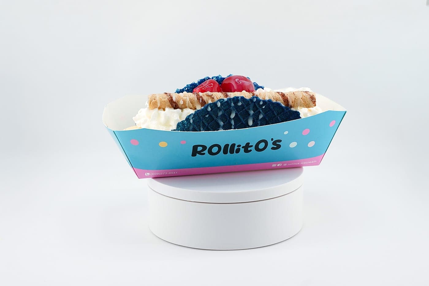Blue waffle taco roll with whipped cream, wafer rolls, and cherries on top