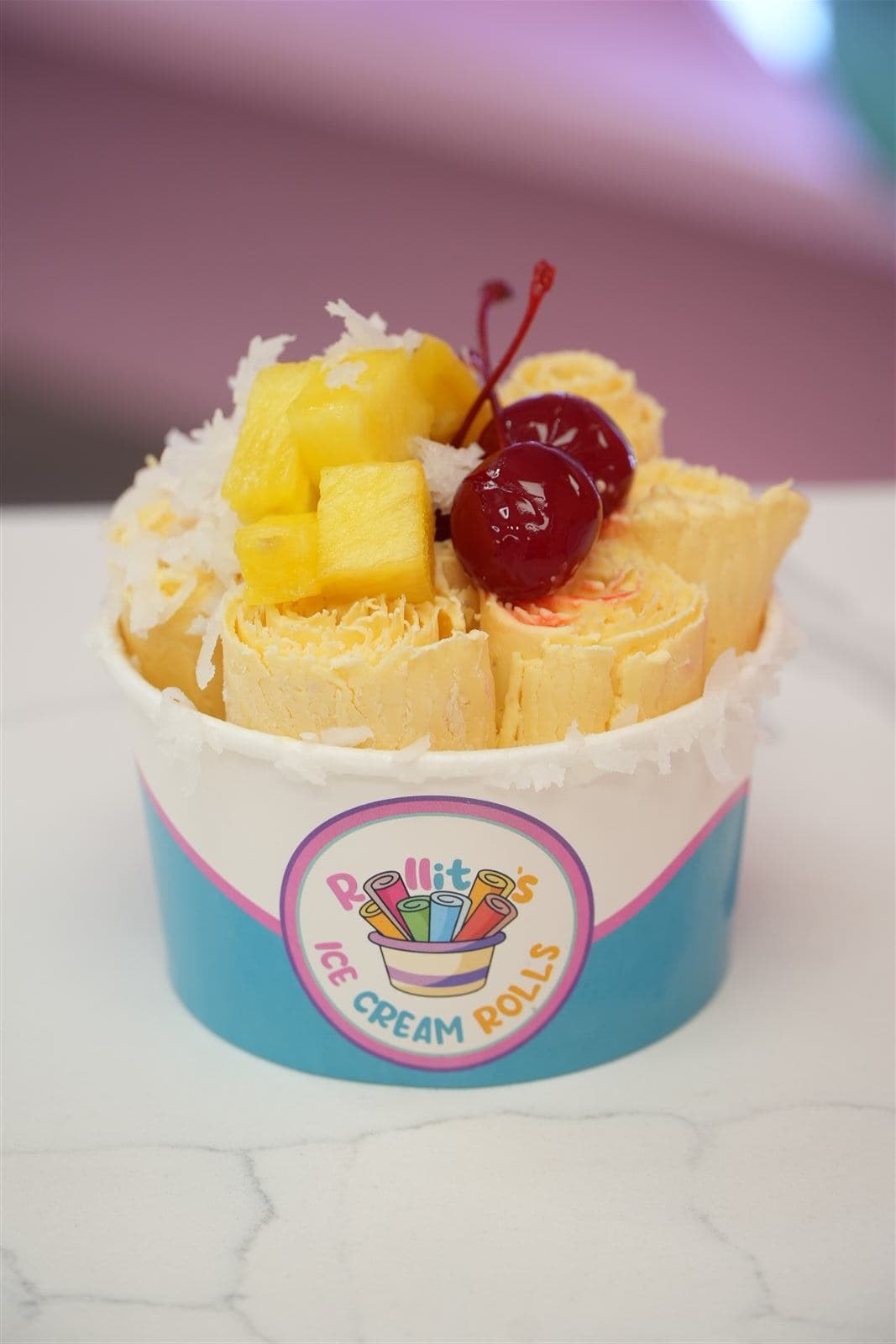 Piña colada ice cream rolls topped with pineapple chunks, cherries, and coconut flakes